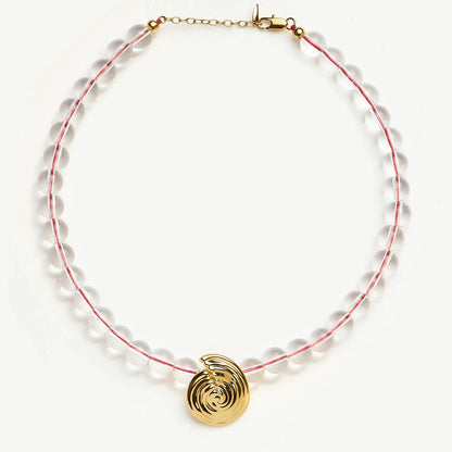 Onda Necklace with spiral wave gold pendant and clear round beads threaded by a red line — symbolizing movement and quiet energy, by MiaPromise.