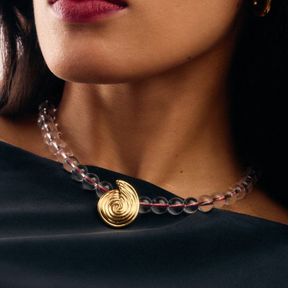 Onda Necklace with spiral wave gold pendant and clear round beads threaded by a red line — symbolizing movement and quiet energy, by MiaPromise.