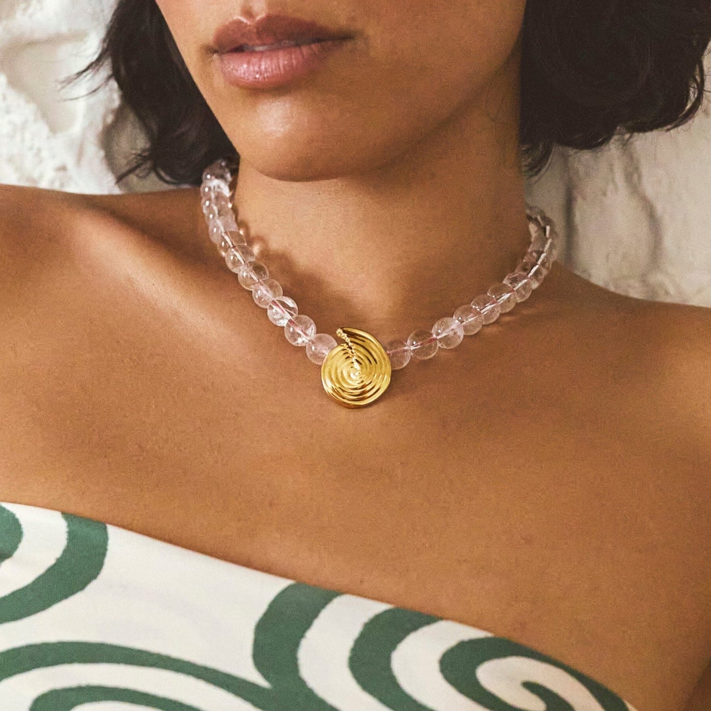 Onda Necklace with spiral wave gold pendant and clear round beads threaded by a red line — symbolizing movement and quiet energy, by MiaPromise.