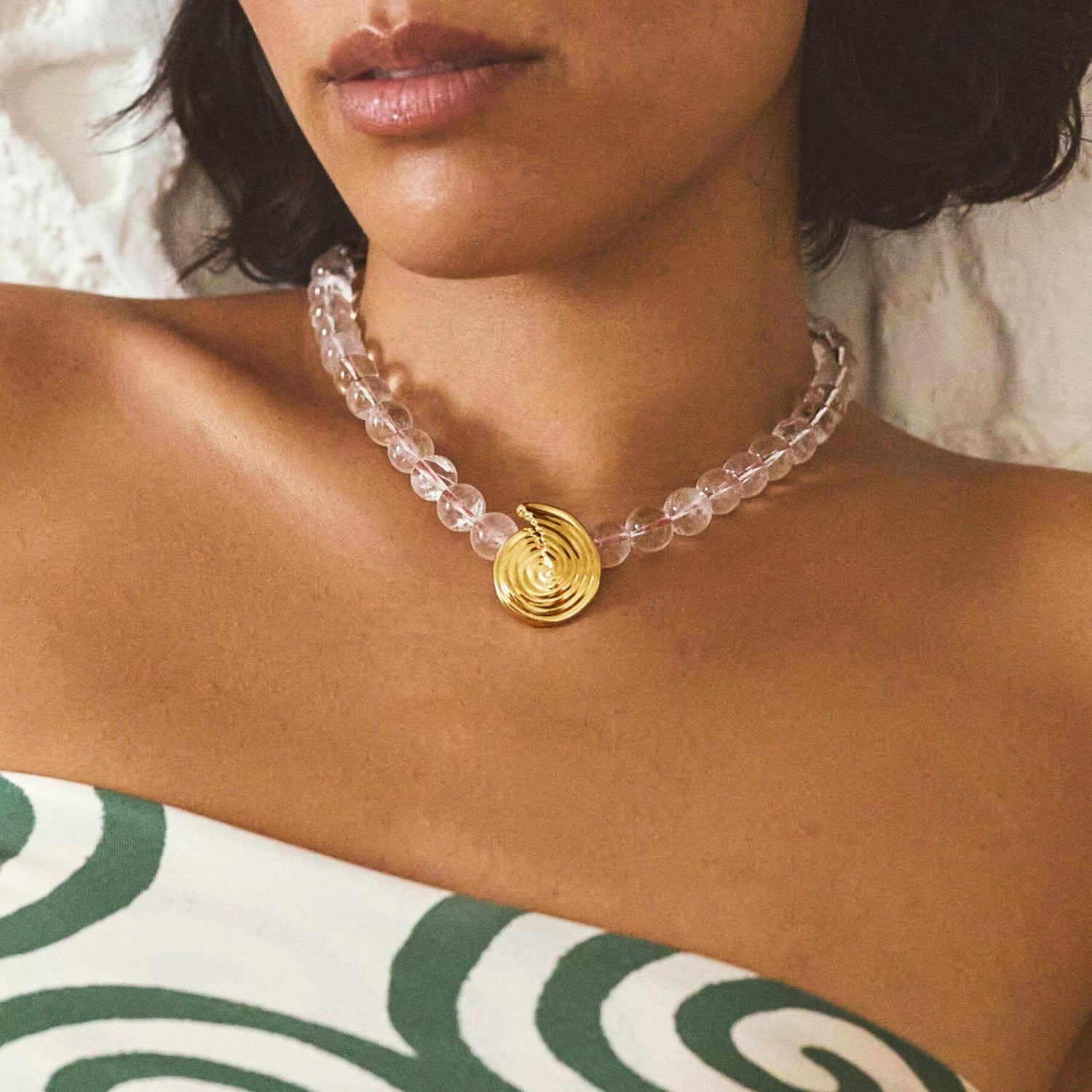 Onda Necklace with spiral wave gold pendant and clear round beads threaded by a red line — symbolizing movement and quiet energy, by MiaPromise.
